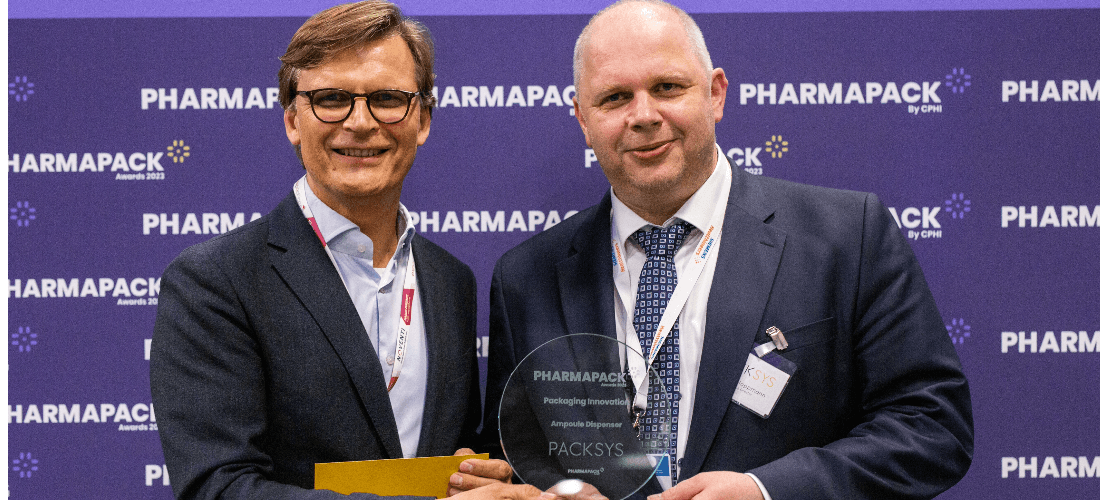 Two pharma professionals holding award on stage at Pharmapack event