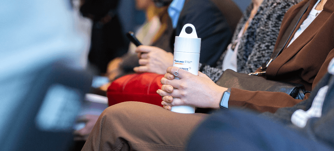 Person sat down holding water bottle at Pharmapack event